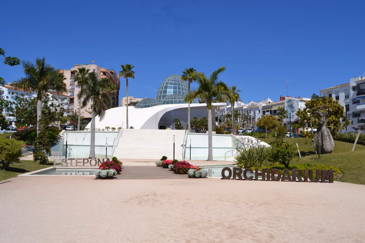 INSUR SCALA: Estepona Orchidarium exterior — glass dome, white curved architecture, palm trees and public gardens