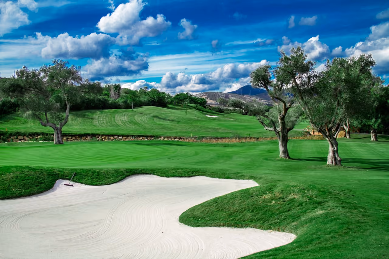 Finca Cortesín golf course — sand bunkers, olive trees, manicured fairways and Andalusian hills, Casares, Costa del Sol, shown as local context near VILLA EVANIA CORTESÍN