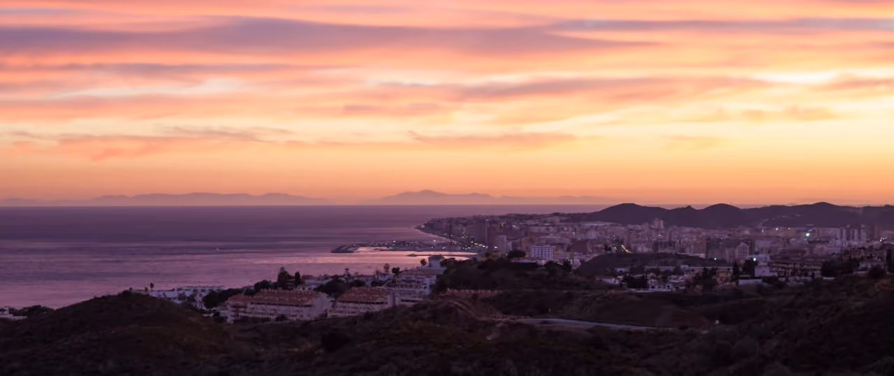 THE KOS: panoramic sunset view over Fuengirola's coastline, harbour, town and the Mediterranean Sea from the Higuerón hillside, Costa del Sol, Spain